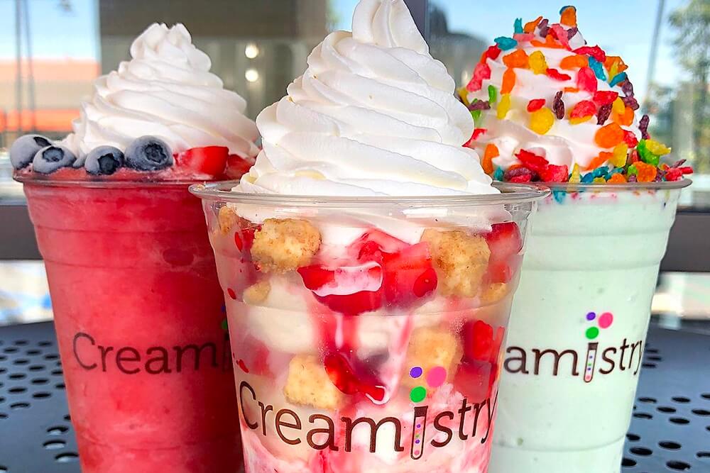 Three bright-colored smoothies topped with whip cream.