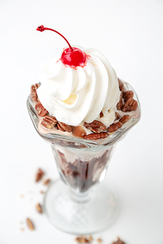 Vanilla ice cream sundae with pecans and a cherry on top