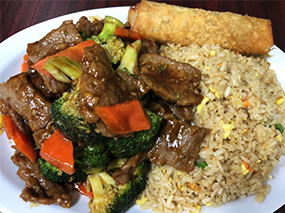 Plate of beef teriyaki with fried rice and an egg roll.