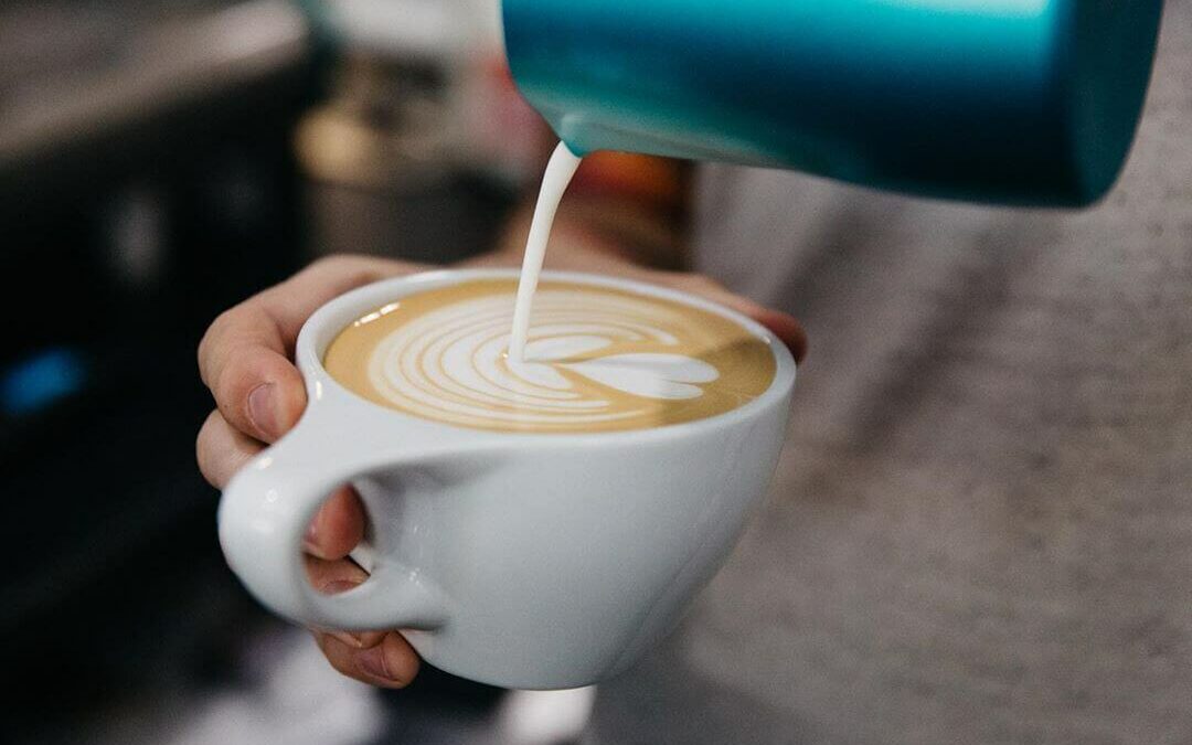 Barista making latte art with steamed milk