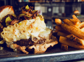 Burger stuffed with mac and cheese and a side of fries.