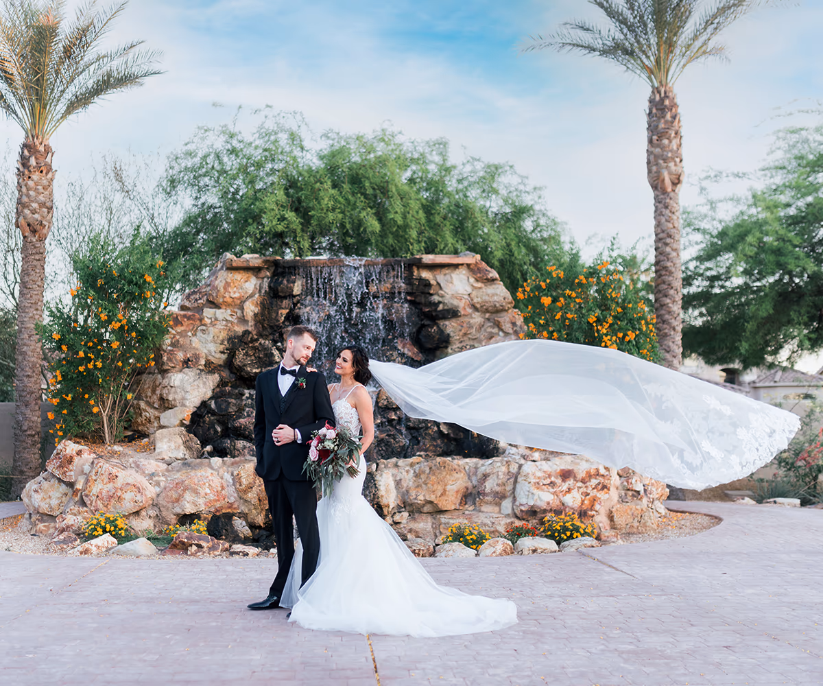 Bride and groom in front of outdoor water feature