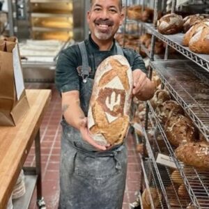 Award Winning Baker Don Guerra holding a loaf of sourdough in a commercial kitchen