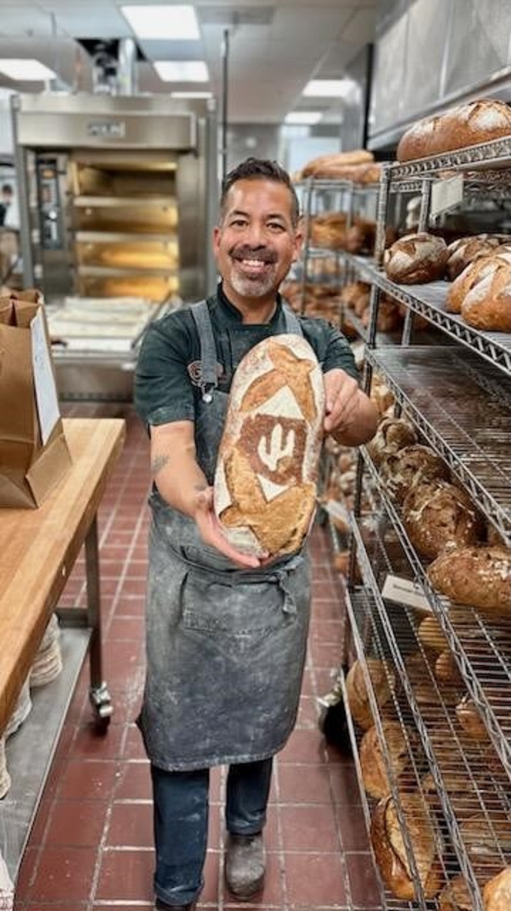Award Winning Baker Don Guerra holding a loaf of sourdough in a commercial kitchen